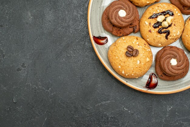 Vista dall'alto deliziosi biscotti dolci deliziosi dolci per il tè sulla scrivania grigia