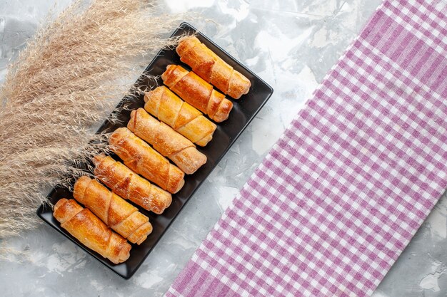 Vista dall'alto deliziosi braccialetti cotti all'interno di stampo nero sulla torta di zucchero pasticceria dolce da scrivania grigio chiaro