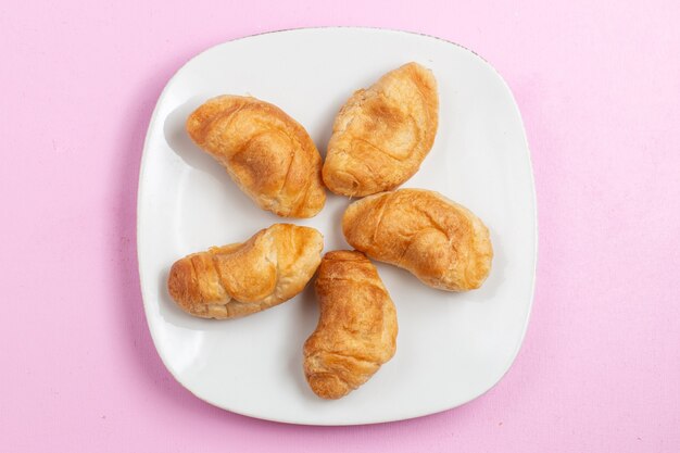 Vista dall'alto deliziosi croissant al forno con ripieno di frutta all'interno sulla scrivania rosa