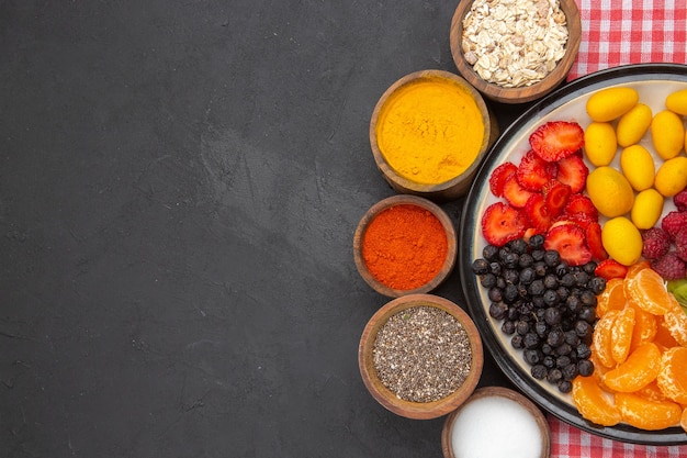 Vista dall'alto deliziosi frutti a fette all'interno del piatto con condimenti su sfondo scuro