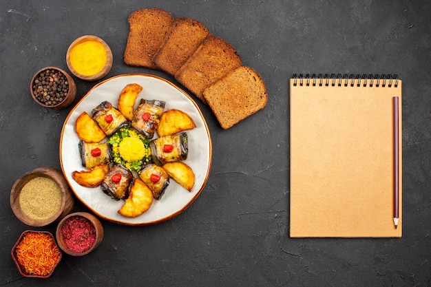 Vista dall'alto deliziosi involtini di melanzane piatto cotto con pane di patate e condimenti su sfondo scuro cucinare cibo piatto di patate fritte cuocere