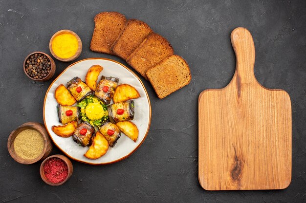 Vista dall'alto deliziosi involtini di melanzane piatto cotto con pane di patate e condimenti sullo sfondo scuro piatto per cucinare cibo fritto di patate cuocere