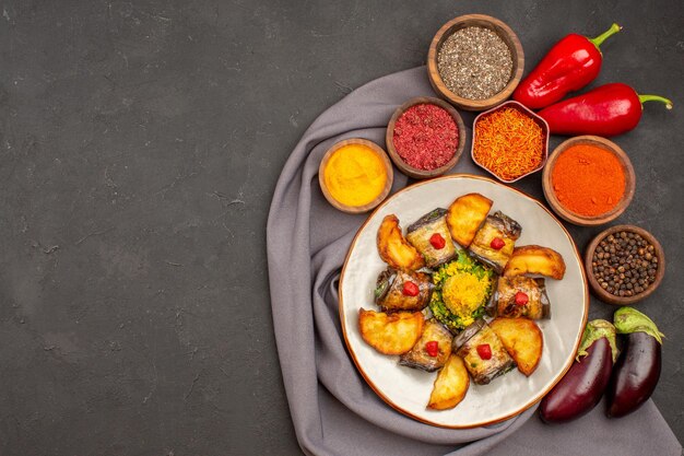 Vista dall'alto deliziosi involtini di melanzane piatto cucinato con patate al forno e condimenti sullo sfondo scuro piatto alimentare piatto di patate