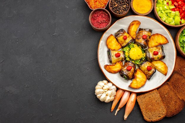 Vista dall'alto deliziosi involtini di melanzane piatto cucinato con patate e pagnotte di pane su una scrivania scura per cucinare cibo friggere piatto cuocere patate