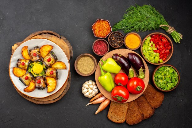 Vista dall'alto deliziosi involtini di melanzane piatto cucinato con patate e verdure su sfondo scuro cucinando piatto di cibo cuocere patate fritte