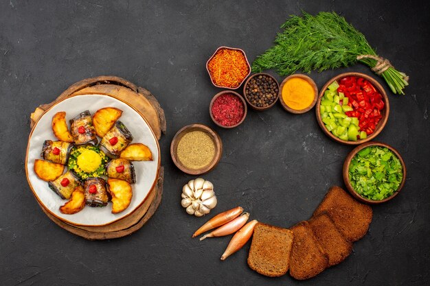 Vista dall'alto deliziosi involtini di melanzane piatto cucinato con patate e verdure su sfondo scuro cucinando piatto di cibo cuocere patate fritte