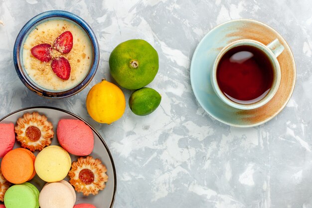 Vista dall'alto deliziosi macarons francesi con biscotti dessert e tè su sfondo bianco chiaro cuocere torta biscotto zucchero dolce foto