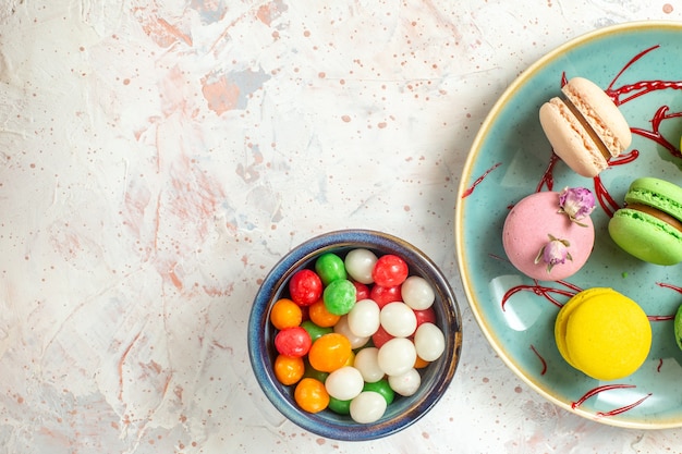 Vista dall'alto deliziosi macarons francesi con caramelle su biscotto dolce bianco chiaro