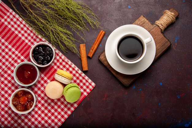 Vista dall'alto deliziosi macarons francesi con marmellate di frutta e tazza di caffè su sfondo scuro dolce marmellata di frutta torta biscotto zucchero dolce