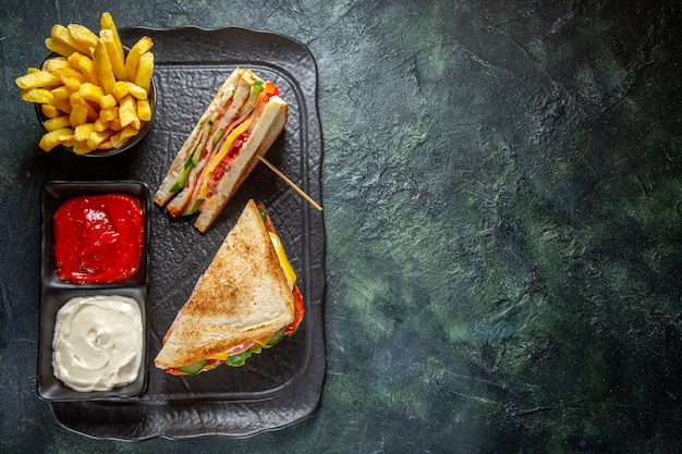 Vista dall'alto deliziosi panini al prosciutto con patatine fritte e condimenti superficie scura