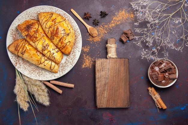 Vista dall'alto deliziosi pasticcini al forno con dessert al cioccolato in uno spazio scuro
