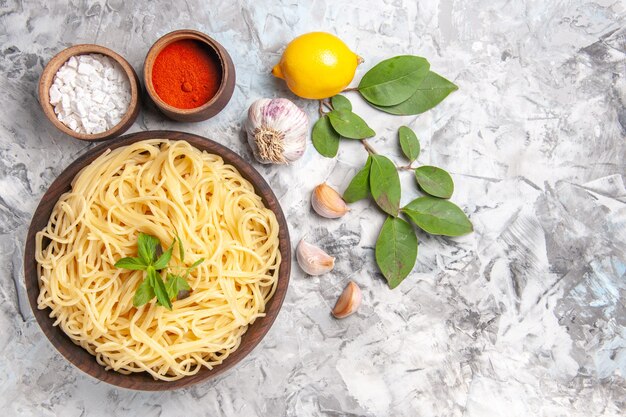 Vista dall'alto deliziosi spaghetti con condimenti su tavola bianca cena pasta pasta pasto