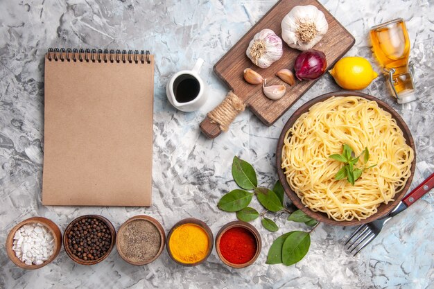 Vista dall'alto deliziosi spaghetti con condimenti sul colore della pasta della pasta da tavola bianca