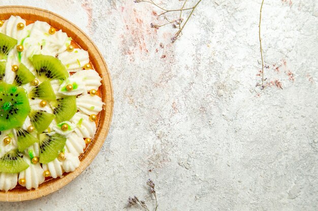 Vista dall'alto delizioso dessert al kiwi con crema bianca squisita e frutta a fette su fondo bianco torta di dessert crema di frutta tropicale