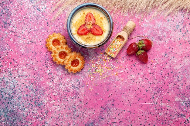 Vista dall'alto delizioso dessert cremoso con fragole rosse a fette e piccoli biscotti su sfondo rosa chiaro dessert gelato alla crema di bacche dolci frutti