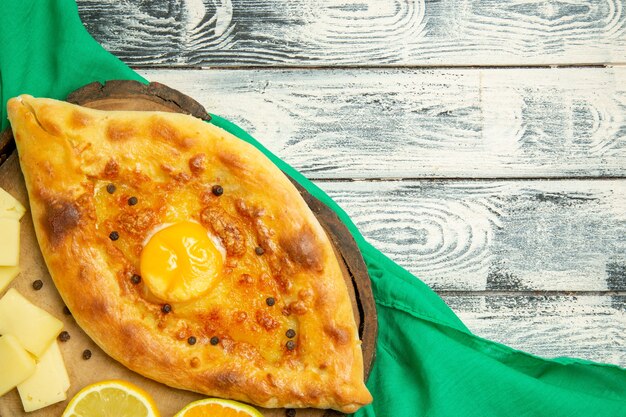 Vista dall'alto delizioso pane all'uovo cotto con formaggio su una scrivania grigia rustica