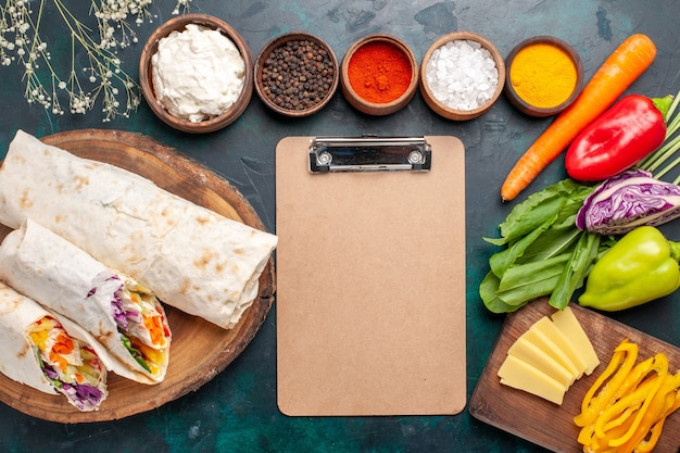 Vista dall'alto delizioso panino di carne fatto di carne alla griglia allo spiedo con condimenti e verdure sulla scrivania blu panino hamburger carne cibo pasto pranzo