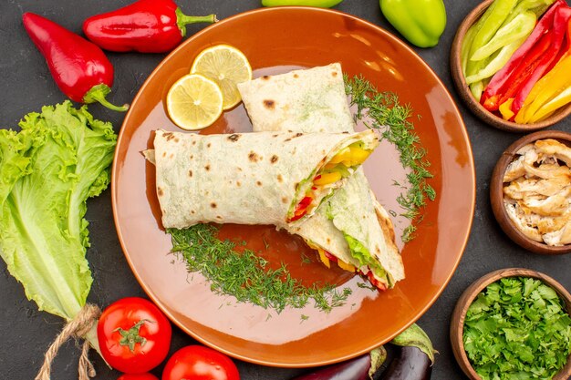 Vista dall'alto delizioso panino shaurma affettato con verdure e verdure su uno sfondo scuro spuntino panino con panino con hamburger