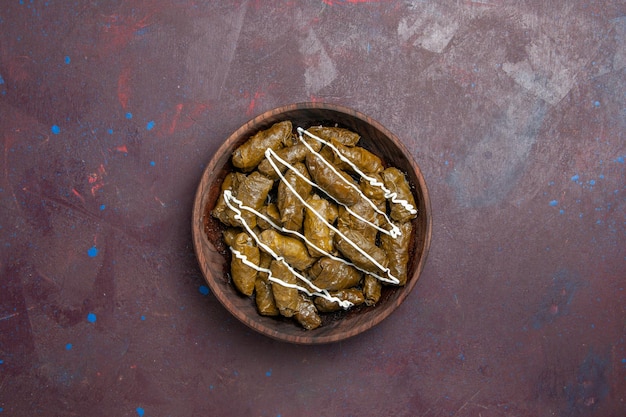 Vista dall'alto delizioso piatto orientale dolma con foglie e carne macinata all'interno su uno sfondo scuro olio calorico cena cibo a base di carne