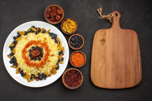 Vista dall'alto delizioso plov con uvetta diversa all'interno del piatto nello spazio buio