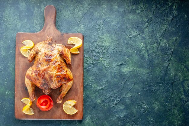 Vista dall'alto delizioso pollo cotto con fette di limone su superficie blu scuro