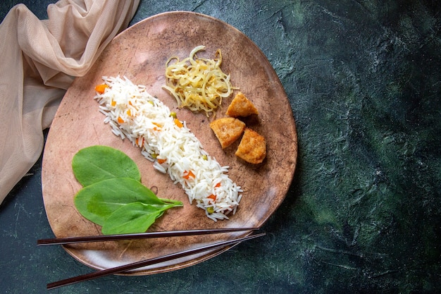 Vista dall'alto delizioso riso con foglie verdi di fagioli e carne all'interno del piatto sulla scrivania scura