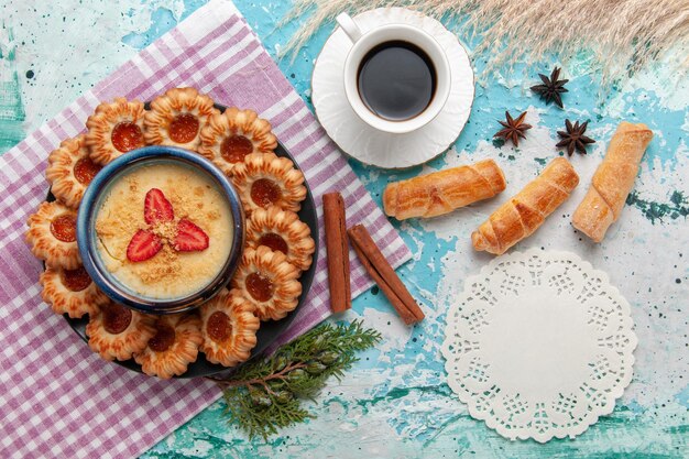 Vista dall'alto delizioso zucchero con tazza di caffè bagel e dessert alla fragola su superficie blu