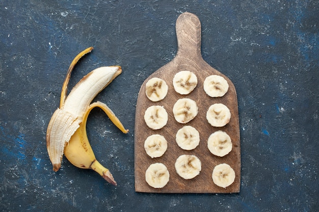 vista dall'alto della banana gialla fresca dolce e deliziosa sbucciata e affettata sulla scrivania blu scuro, frutta dolce vitamina salute