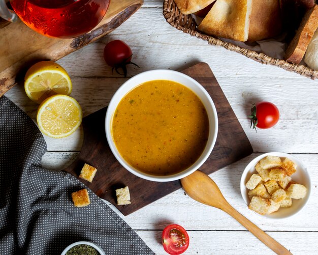 Vista dall'alto della ciotola di zuppa di lenticchie servita con fettine di limone e ripieno di pane