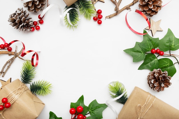 Vista dall'alto della composizione in Natale con confezione regalo, nastro, rami di abete, coni, anice sul tavolo bianco