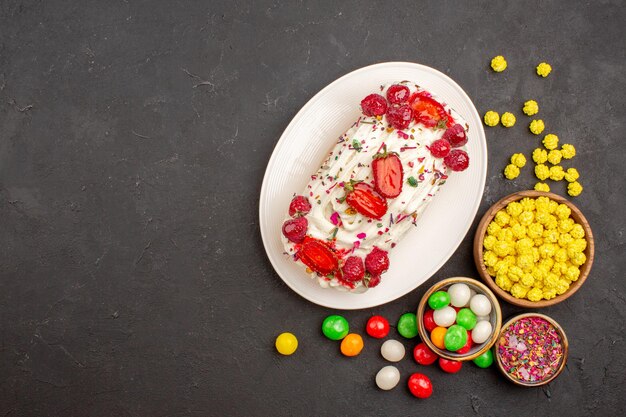 Vista dall'alto della deliziosa torta fruttata con caramelle su grigio scuro dark