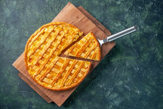 Vista dall'alto della deliziosa torta kumquat con un pezzo a fette sulla superficie scura