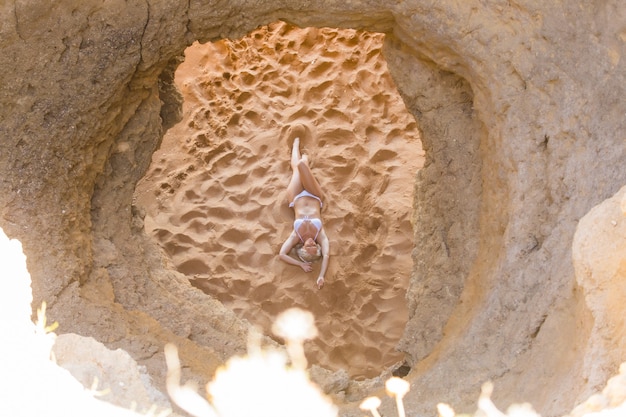 Vista dall'alto della donna che si distende sull'idilliaca spiaggia tropicale sdraiata sulla spiaggia sabbiosa mentre le onde schizzano su di essa