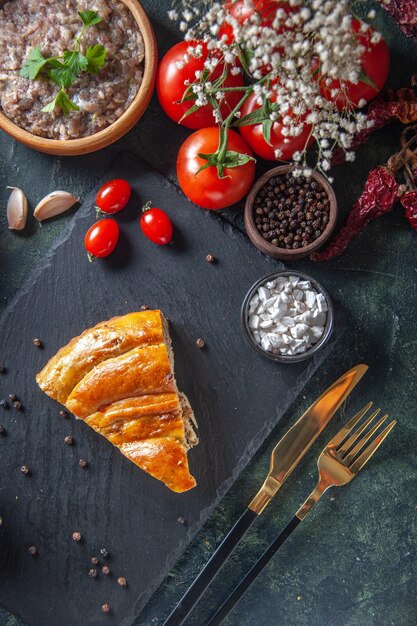 Vista dall'alto della fetta di torta di carne gustosa con pomodori rossi e carne ripiena sulla superficie scura