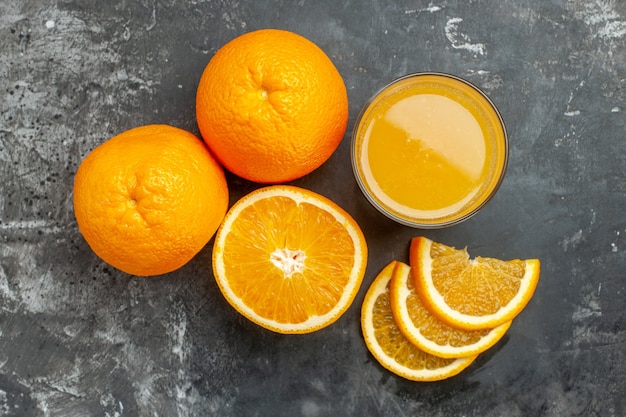 Vista dall'alto della fonte di vitamina tagliata arance e succo freschi tritati e interi su sfondo grigio