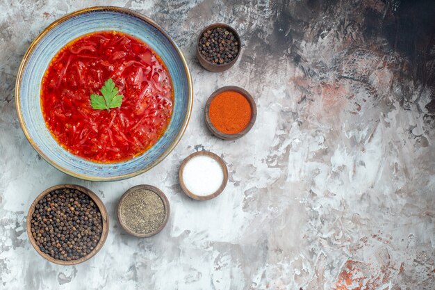 Vista dall'alto della gustosa zuppa di barbabietola ucraina borsch con condimenti sulla superficie bianca