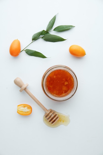 Vista dall'alto della marmellata di mele cotogne in barattolo di vetro e kumquat con mestolo di marmellata su sfondo bianco