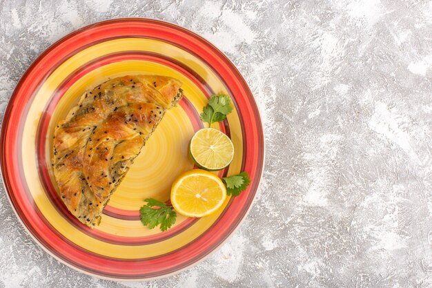 Vista dall'alto della pasticceria con farina di pasta deliziosa a base di carne all'interno del piatto affettato con limone su superficie bianco chiaro