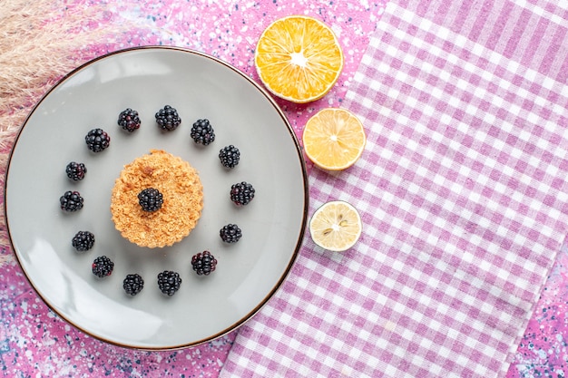 Vista dall'alto della piccola torta con frutti di bosco sulla superficie rosa