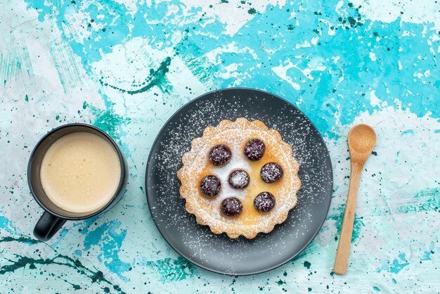Vista dall'alto della piccola torta con zucchero in polvere e frutta insieme al latte sulla scrivania a luce blu, torta di frutta dolce zucchero