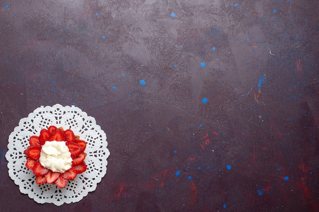 Vista dall'alto della piccola torta cremosa con frutta a fette sulla superficie scura