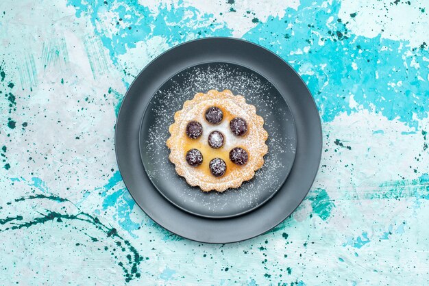 vista dall'alto della piccola torta di zucchero in polvere con frutta all'interno della piastra sulla scrivania con luce blu, torta di frutta cuocere dolce