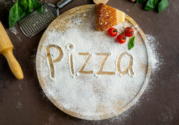 Vista dall'alto della pizza scritta nella farina con parmigiano e pomodori