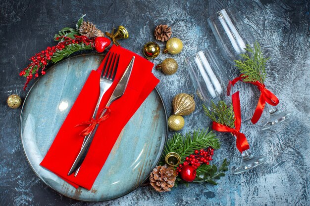 Vista dall'alto della preparazione natalizia con disposizione del tavolo e accessori per la decorazione di rami di abete e cono di conifere su sfondo scuro