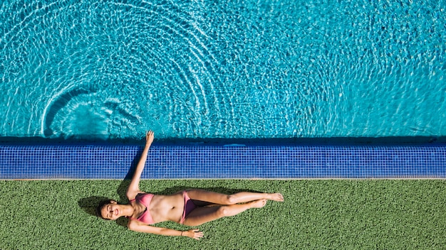 Vista dall&#39;alto della ragazza rilassante accanto alla piscina