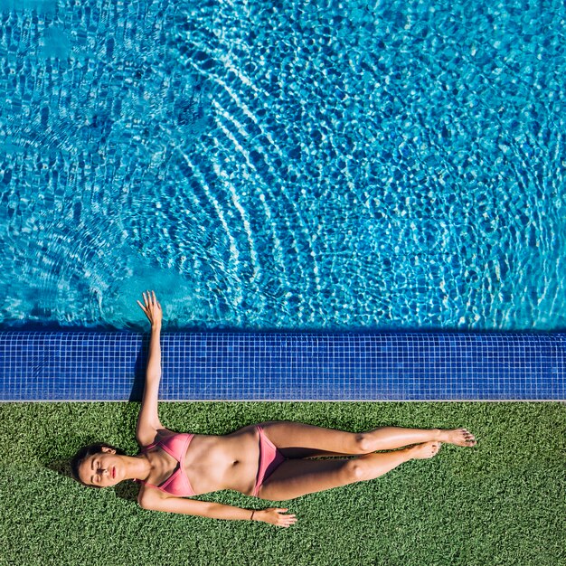 Vista dall&#39;alto della ragazza rilassante accanto alla piscina