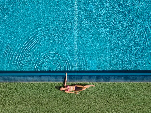 Vista dall&#39;alto della ragazza rilassante accanto alla piscina