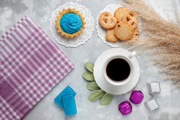 Vista dall'alto della tazza di tè con deliziosi biscotti al cioccolato caramelle sul pavimento bianco, biscotto biscotto caramelle chocoalte