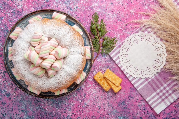 Vista dall'alto della torta di zucchero a velo con cracker sulla superficie rosa
