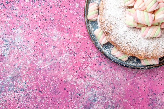 Vista dall'alto della torta di zucchero a velo con marshmallow dolce sulla superficie rosa